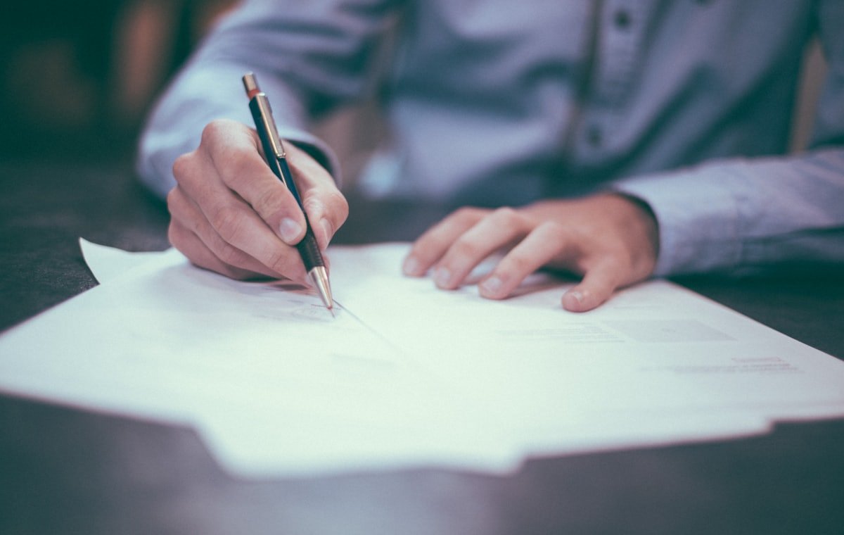 Manos firmando un documento laboral sobre un escritorio